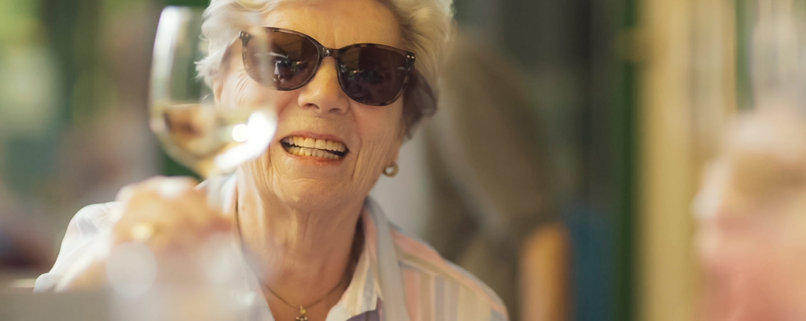 Glückliche WohnGut-Bewohnerin hebt ein Glas Wein zum Anstoßen nach oben