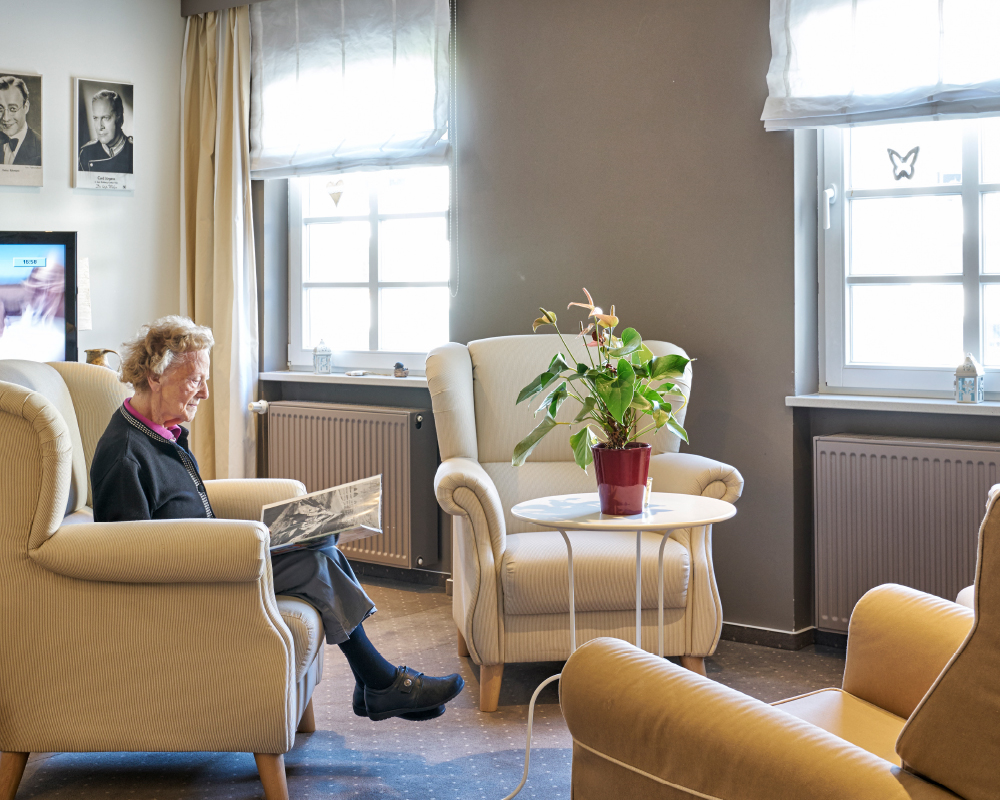 Bewohnerin sitzt in einer gemütlichen Sitzecke im Pflege-Wohnen im WohnGut Osterseifen
