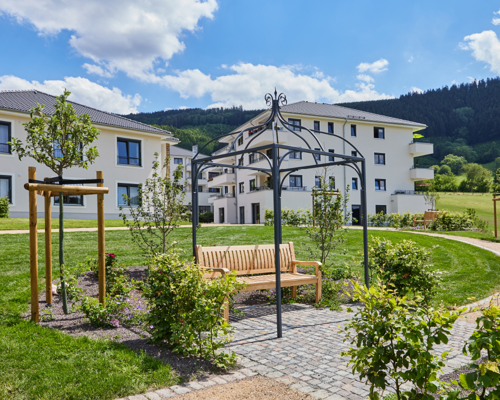 Außenansicht Gebäude Service-Wohnen und Parkanlage mit Bank im WohnGut Saalhausen