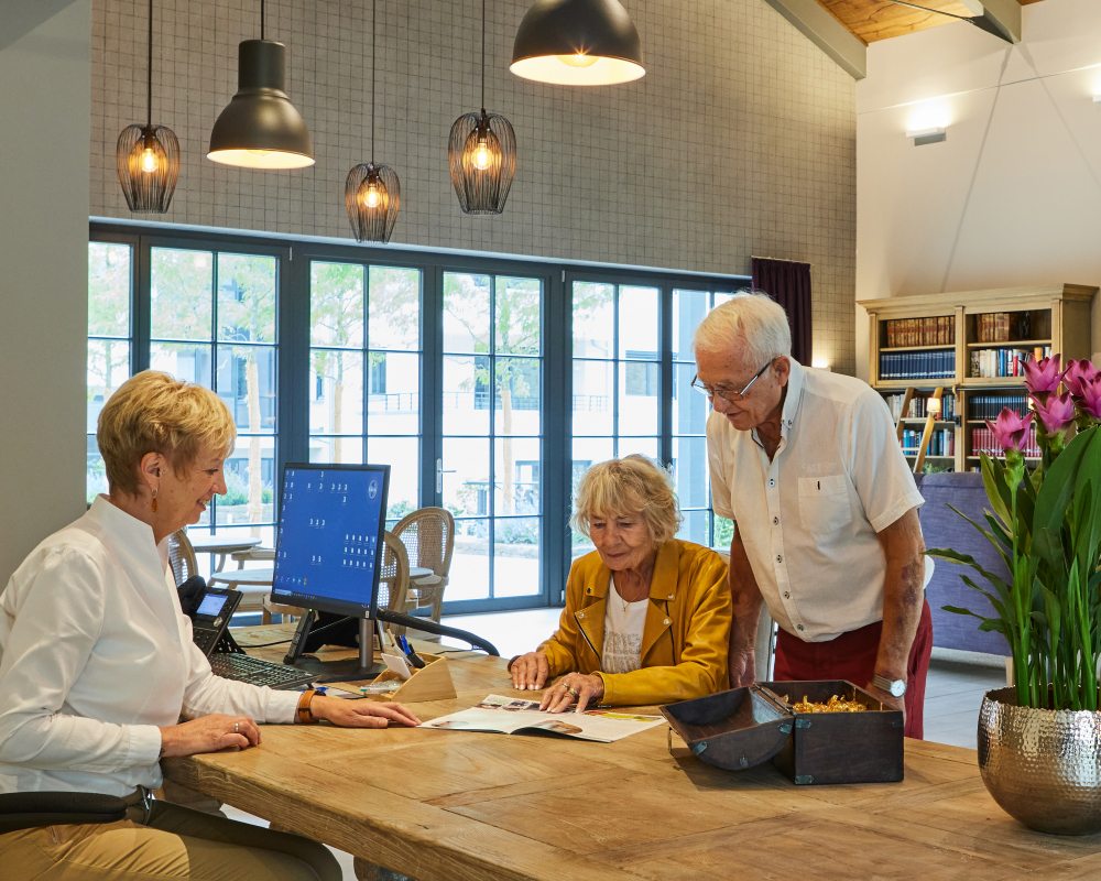 Rezeptionistin mit Bewohnerpaar an der Rezeption im WohnGut Saalhausen