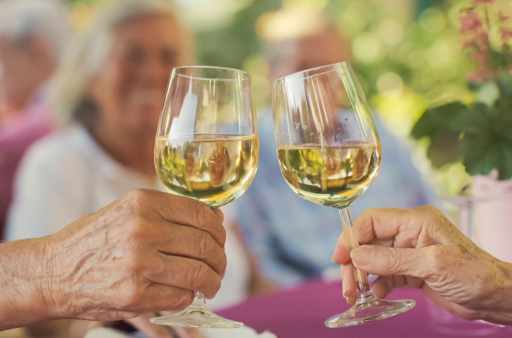 Bewohner stoßen mit Wein im WohnGut an