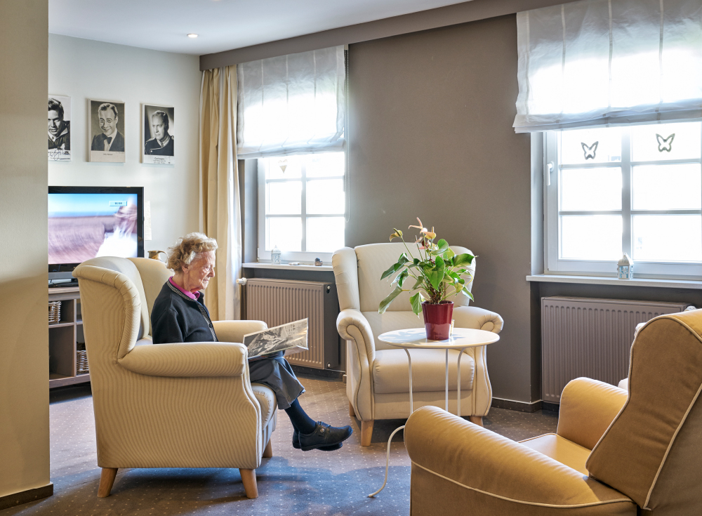 Bewohnerin sitzt in einer gemütlichen Sitzecke im Pflege-Wohnen im WohnGut Osterseifen