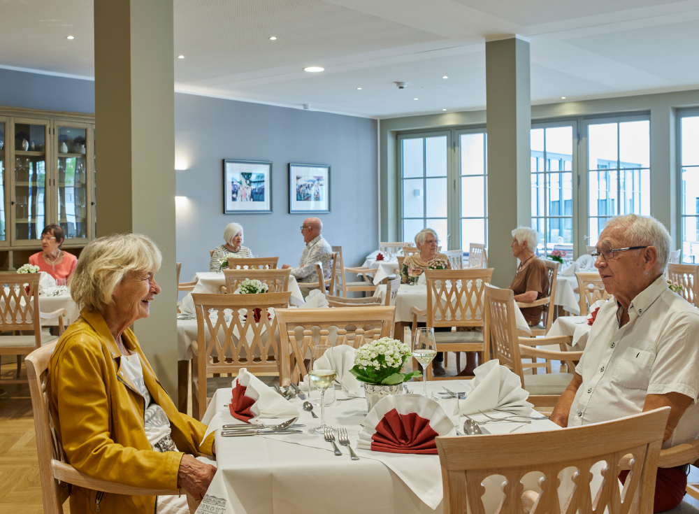 Bewohner sitzen im Restaurant des WohnGut Saalhausen am gedeckten Tisch