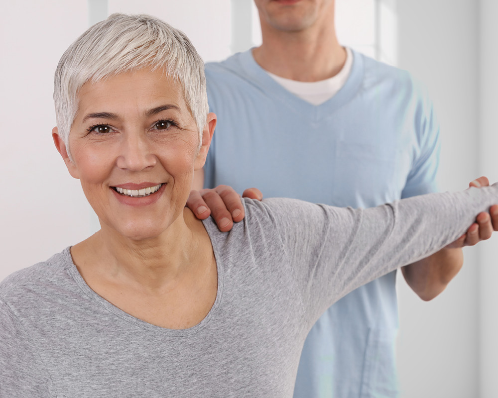 Physiotherapeut behandelt attraktive ältere Frau